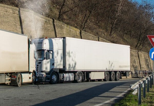 Two large white trucks colliding on a highway